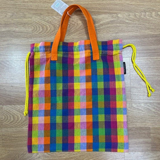 Colorful checkered drawstring bag with orange handles on a wooden surface