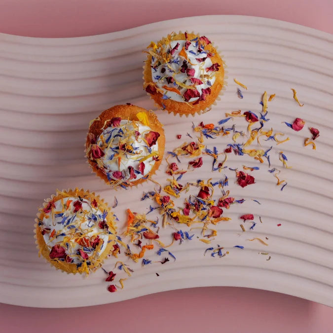 Three small pastries with colorful toppings on a pink surface