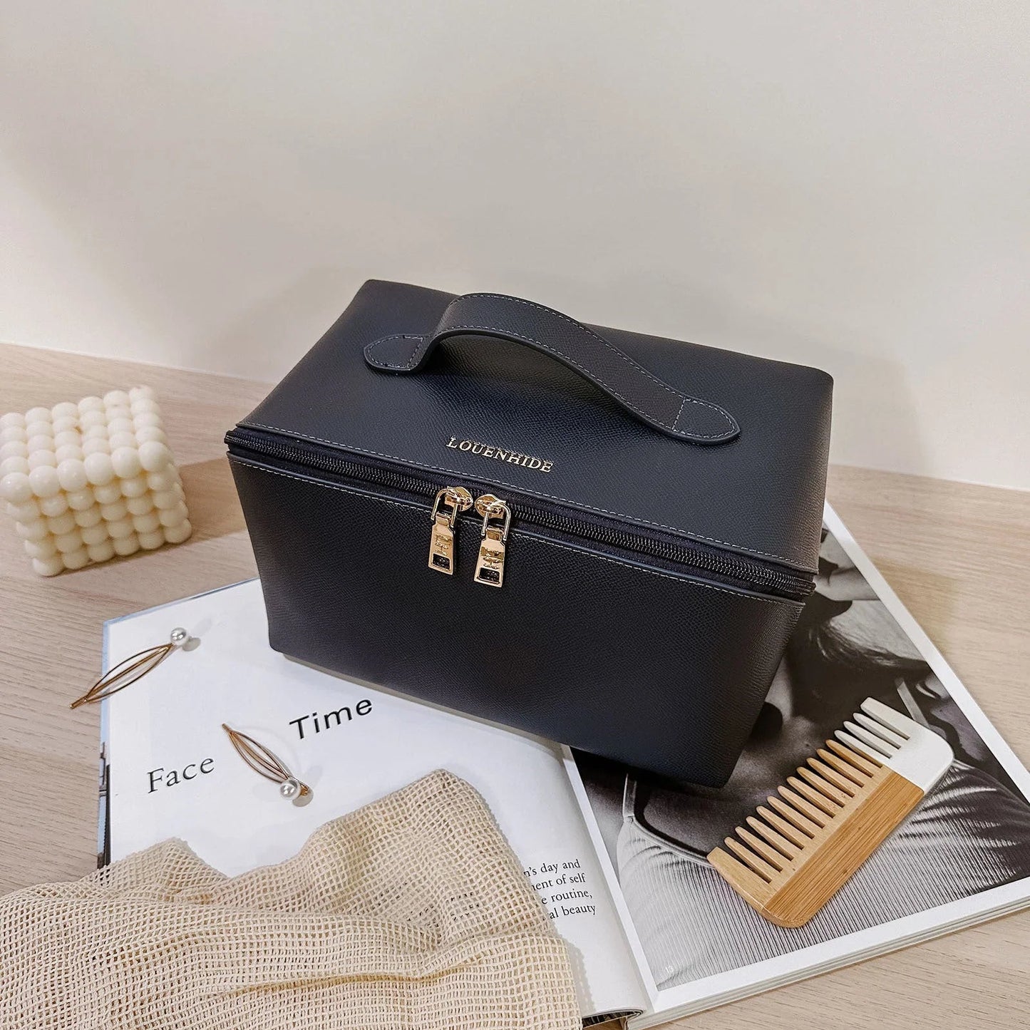 Navy toiletry bag case with gold accents on a magazine with grooming tools