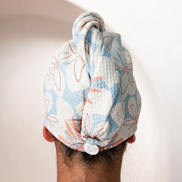 Turban towel with floral pattern on a person's head against a white background