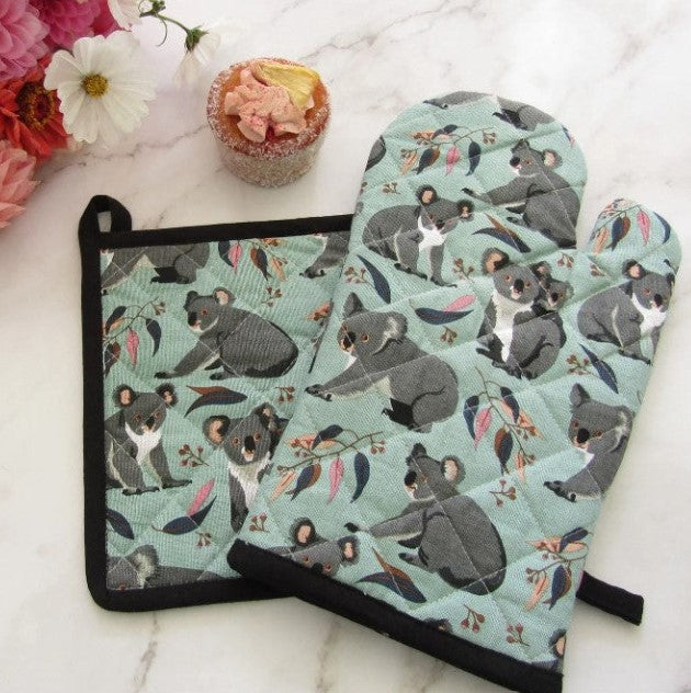 Set of pot holder and oven mitt with koala design on a white surface with flowers.