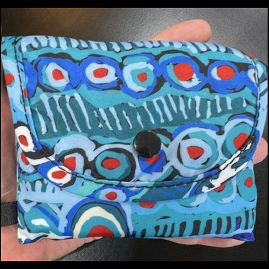 Colorful patterned pouch held by a hand on a dark background