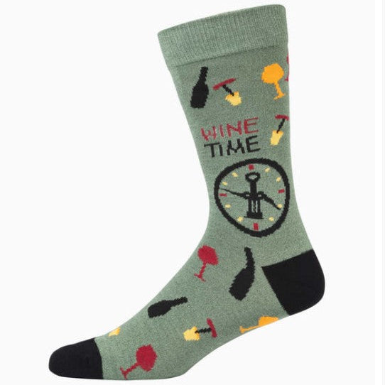 A single crew sock in sage green with a wine-themed pattern, including a corkscrew, wine glasses, a bottle, and the words 'WINE TIME' in red and black, with a black heel and toe.