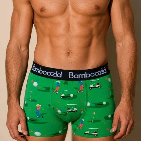 A man wearing green boxer briefs with a golf-themed print and a black Bamboozld waistband, shown from the chest down against a beige studio background.