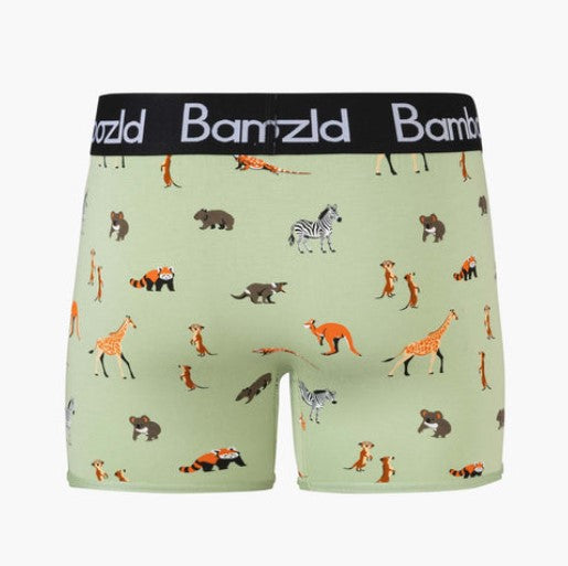 A pair of boxer trunks by Bambzld, featuring a light sage green base with an all-over safari animal print including giraffes, zebras, foxes, and bears. The waistband is black with the brand name 'Bambzld' printed in white.