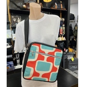 Mannequin wearing a white shirt with a colorful geometric-patterned bag.