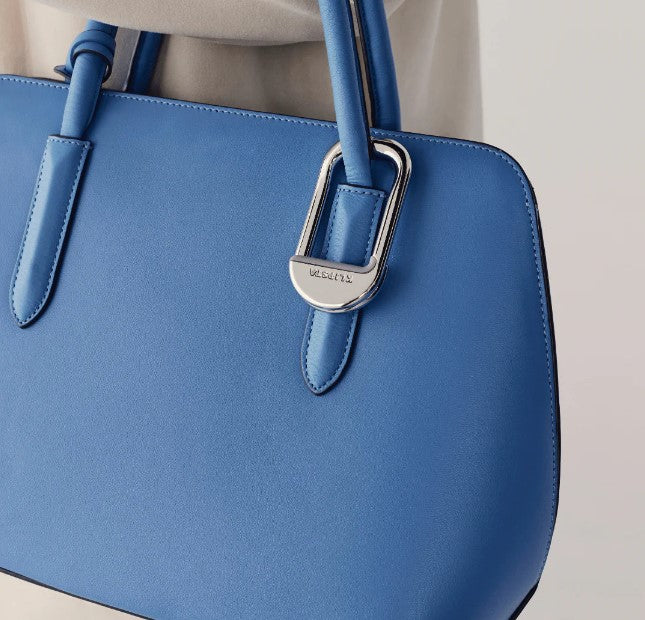 Blue handbag with a silver clasp on a neutral background