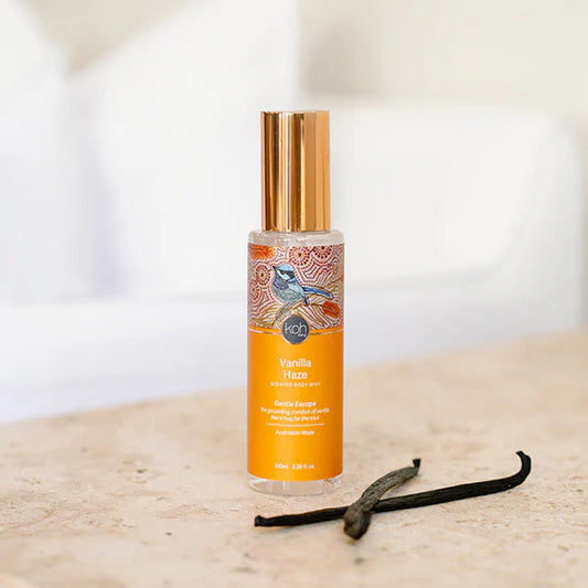 Vanilla haze body mist with a vanilla bean on a wooden surface