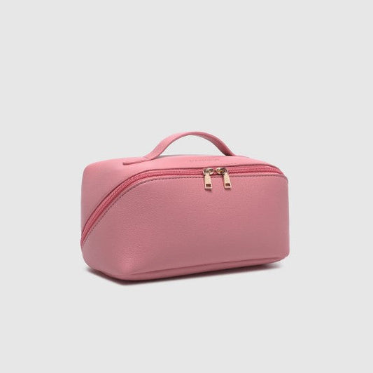 Pink cosmetic bag with gold zippers on a light gray background