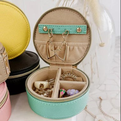 Round jewelry case with compartments filled with jewelry on a light background