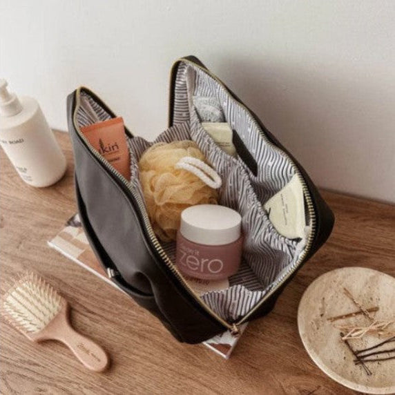 Open travel bag with toiletries on a wooden surface
