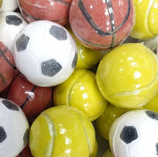 A close-up pile of small plastic sports balls, including white soccer balls with black panels, red basketballs with black lines, and bright yellow tennis balls, all wrapped in clear plastic.