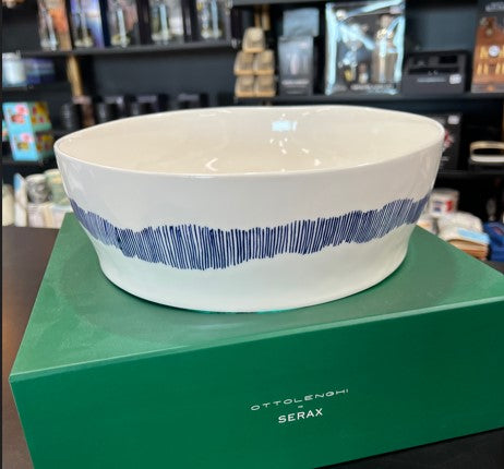 White bowl with blue stripes on a green box labeled 'Ottolenghi Serax' in a store setting.