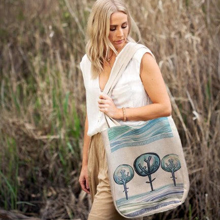 Woman holding a tote bag with tree design in a natural setting