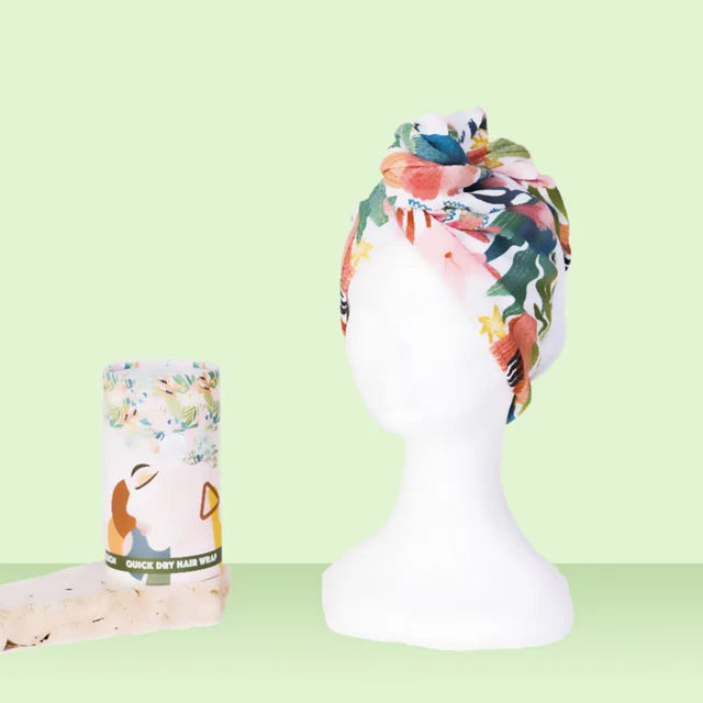 Floral quick dry hair wrap on a mannequin head with a matching cylindrical container on a light green background