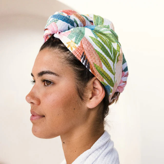 Woman wearing a colorful floral headscarf on a plain background