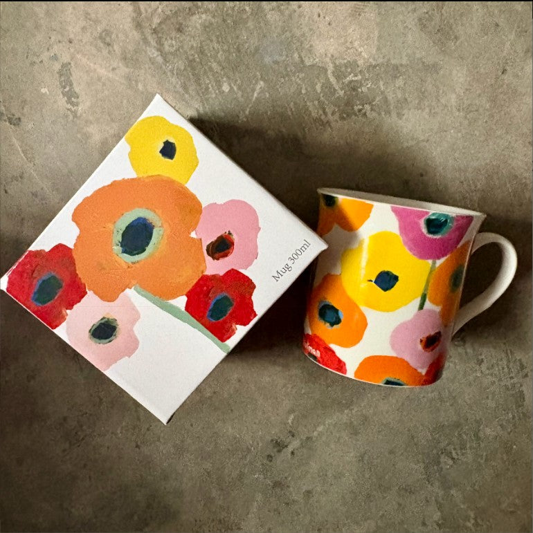 Floral mug and packaging on a concrete surface