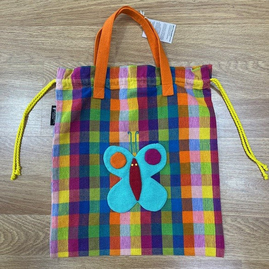 Colorful checkered drawstring bag with a butterfly patch on a wooden surface