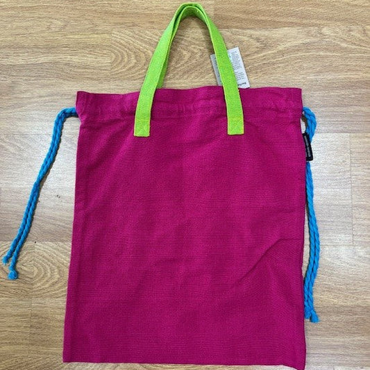 Pink drawstring bag with green handles and blue drawstrings on a wooden surface
