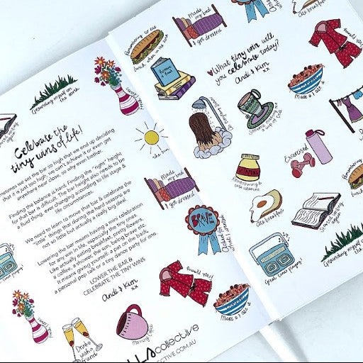 An open notebook or journal spread showing illustrated daily prompts and short poems on white pages, photographed from above on a light background.