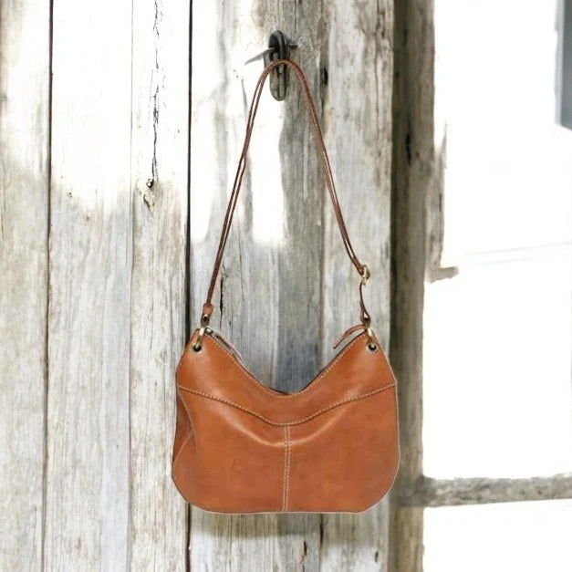 Brown leather handbag hanging on a wooden door