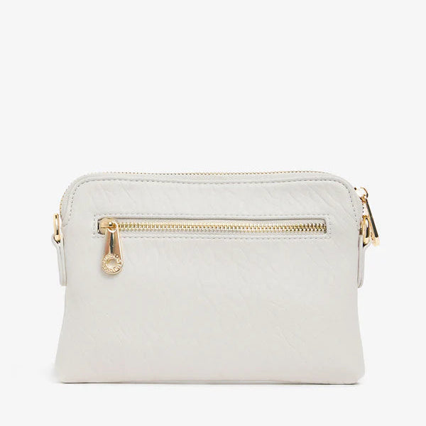 Light gray crossbody bag with gold zipper and hardware on a white background