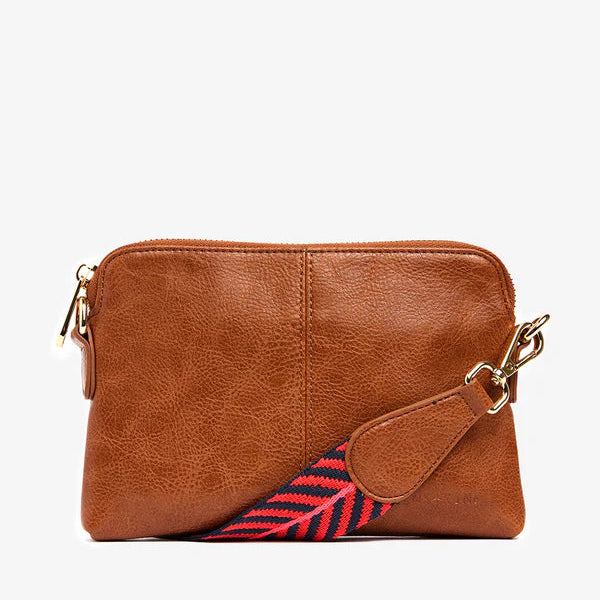 Brown leather crossbody bag with a colorful strap on a white background