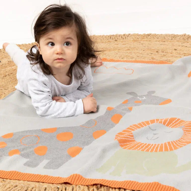 Child lying on a colorful blanket with animal patterns on a white background