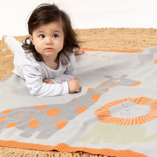 Child lying on a colorful blanket with animal patterns on a white background