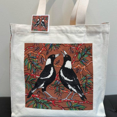 Tote bag with bird design and matching sticker on a neutral background