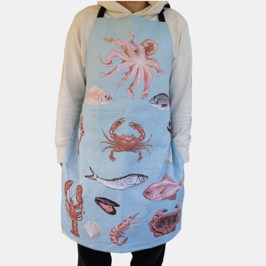 Person wearing a light blue apron with sea creature designs on a white background