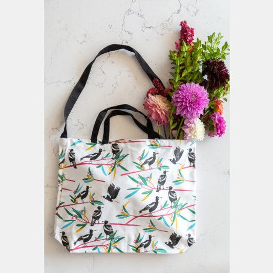 Tote bag with bird design on a marble surface with flowers