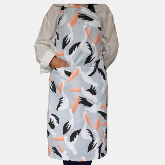 Person wearing a patterned apron with pelicans on a light gray background