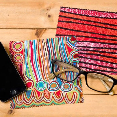 Colorful lens cloth with a phone and glasses on a wooden surface