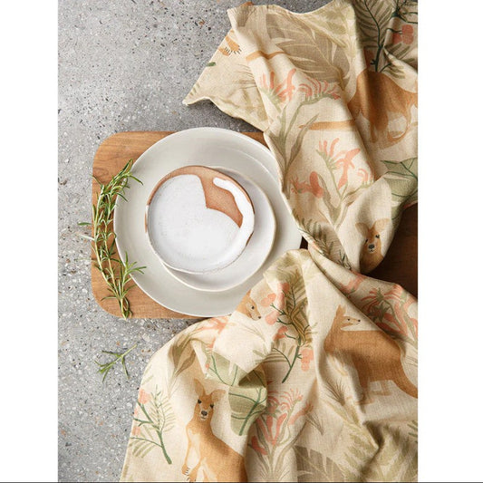 Dinner setting with white plates, a wooden cutting board, and a floral cloth on a textured surface.