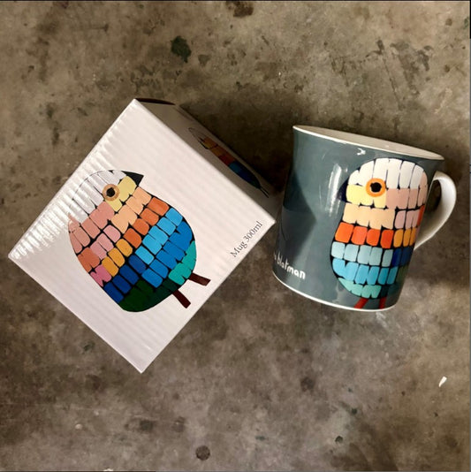 Colorful owl mug and packaging on a concrete surface
