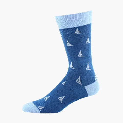 A single crew sock in medium blue with a repeating white sailboat pattern, featuring a light blue ribbed cuff, toe, and heel, shown on a plain white background.
