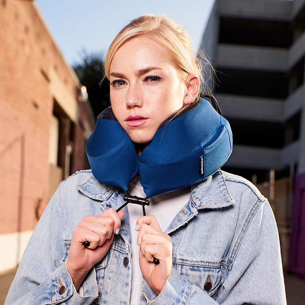 Woman wearing a blue neck pillow outdoors