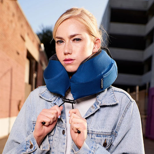 Woman wearing a blue neck pillow outdoors