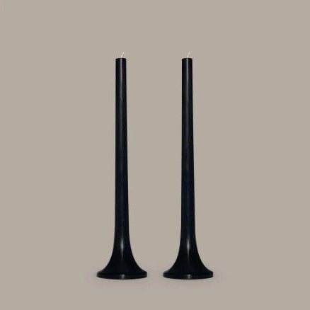 Two black candles on a beige background
