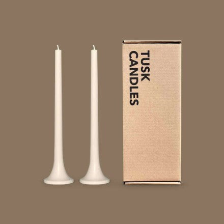 Two white candles and their cardboard box on a brown background