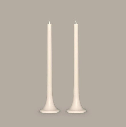 Two white candles with white holders on a beige background