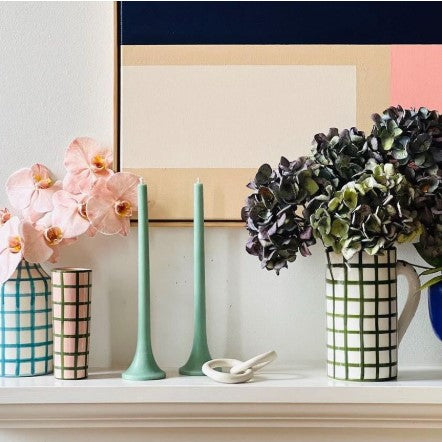 Decorative items including vases, candles, and flowers on a shelf with a colorful abstract painting in the background.