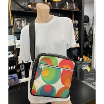 Mannequin wearing a white shirt with a colorful polka dot bag in a store setting