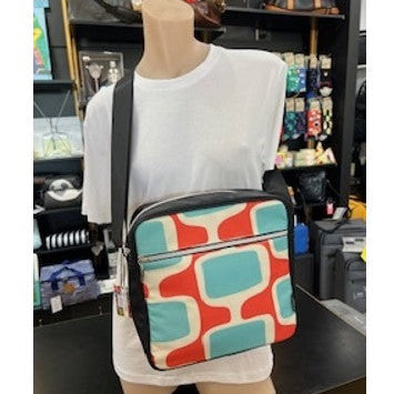 Mannequin wearing a white shirt with a colorful geometric-patterned bag in a store setting.