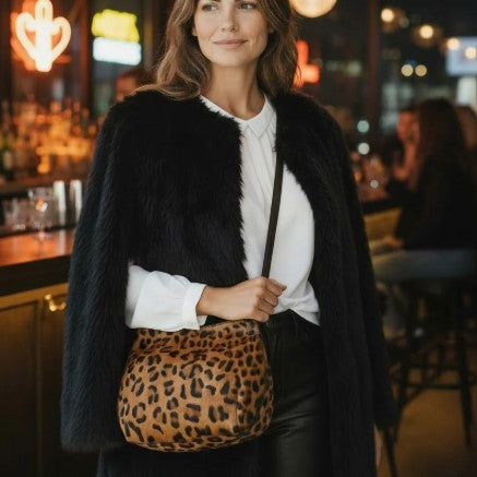 Woman holding a leopard print bag in a bar setting