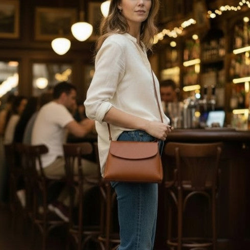Woman holding a brown leather bag in a bar setting