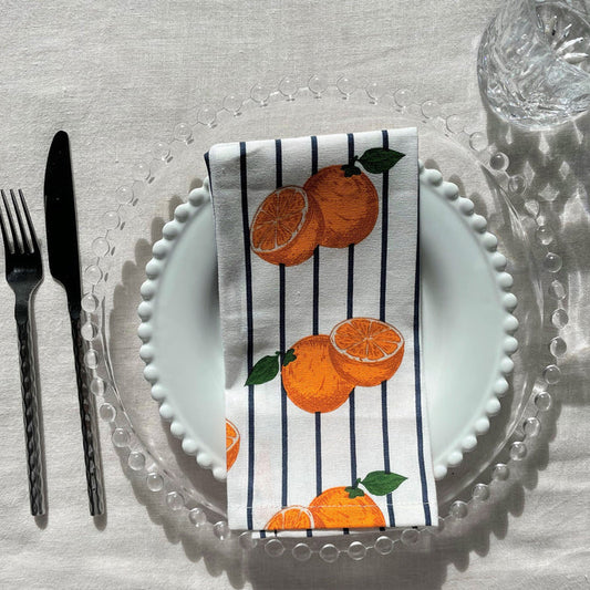 Napkin with orange design on a plate with cutlery