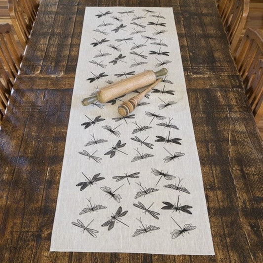 Dragonfly-patterned table runner on a wooden table with a rolling pin and wooden spoons.