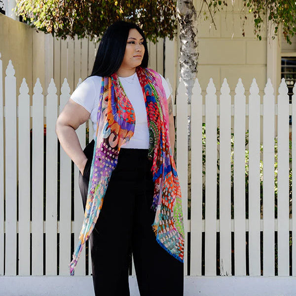 Woman wearing a colorful scarf in front of a white picket fence